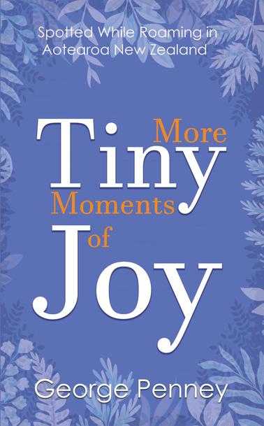 Short Description: You're looking at a blue book cover with the words: Spotted While Roaming in Aotearoa New Zealand, More Tiny Moments of Joy, George Penney on it. Longer Description: The blue is the sort of blue you'd encounter in the sky on a sunny spring day when you turn your face to the sun and smile. There are some paler blue plant silhouettes around the border that promise ferns are in your future because ferns are always in your future when you're walking in New Zealand. The font for the title is the sort that tells you that this book takes fun, sweet and gentle things seriously. Just looking at this cover, you know your blood pressure is going to lower after reading the contents.
